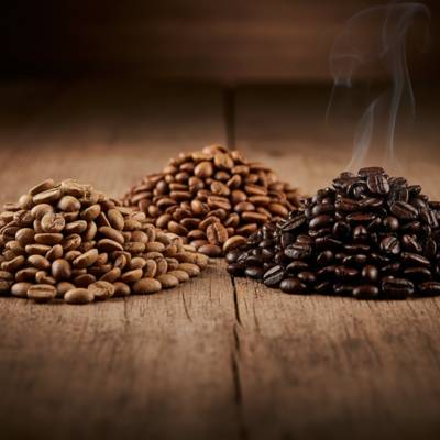 Primo piano di chicchi di caffè a tre livelli di tostatura (chiaro, medio, scuro) per guida al gusto.